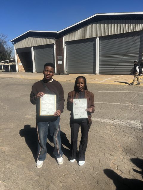 Two learners holding their licences